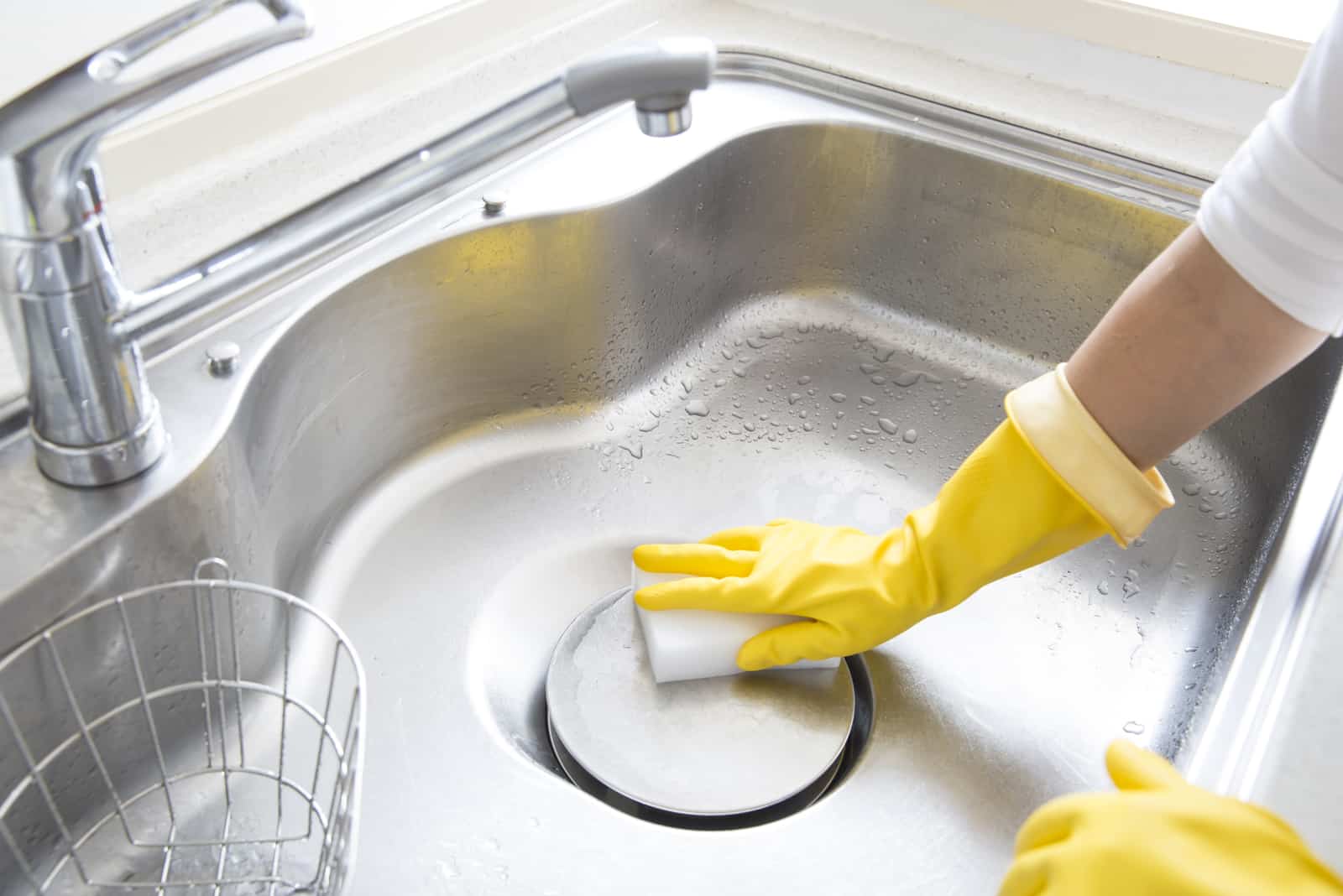 mujer limpiando el fregadero de la cocina