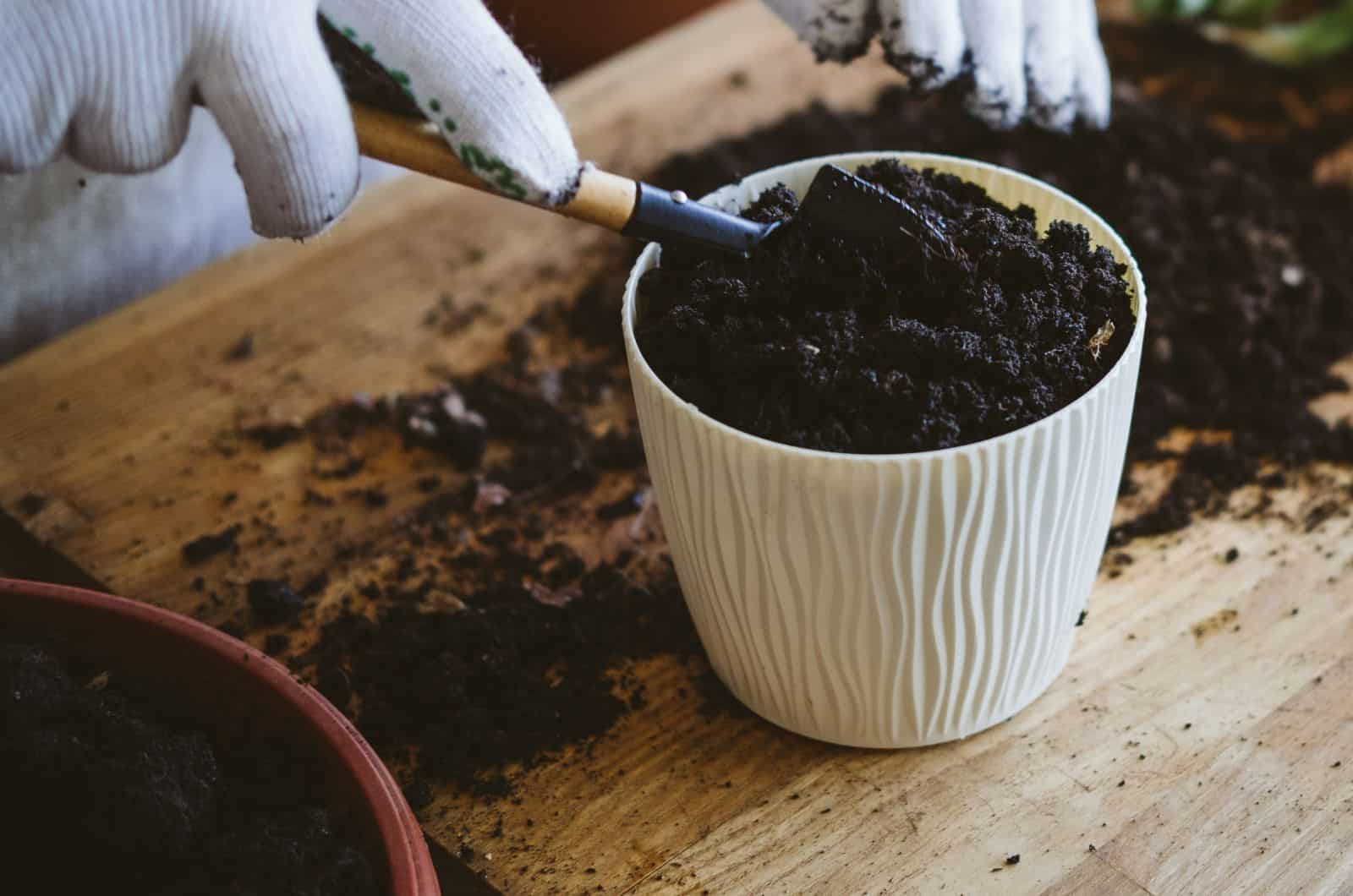 mujer llenando una olla con tierra